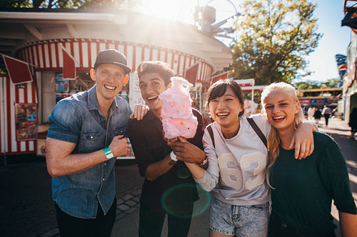 Group of young friends with cotton candy in amusement park