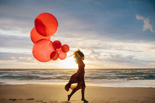 Woman running on the beach with balloons 