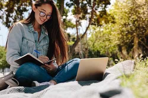 Happy girl studying in a park