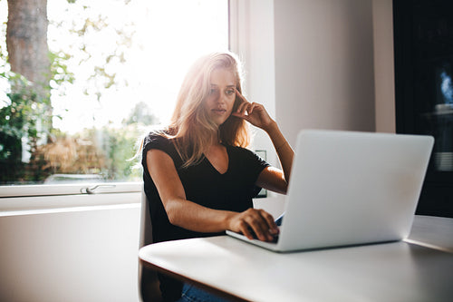 Thoughtful young woman working on laptop