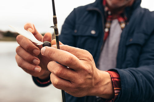 Man fixing bait to his fishing rod to catch fish
