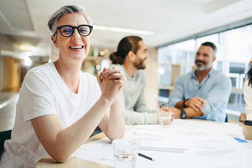 Happy businesswoman attending a meeting with her team in an office
