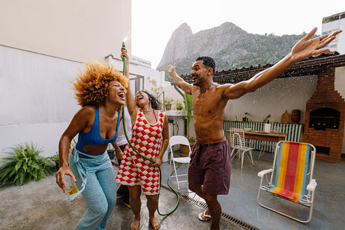 Friends cooling off with water on a hot summer rooftop in Rio
