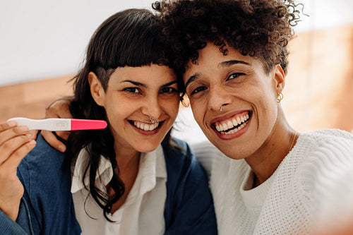 Ecstatic female couple taking a selfie with their positive pregn