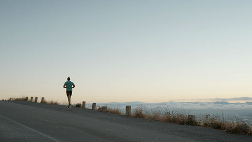 Man running on a mountain road in the morning