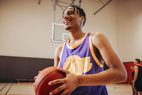 Young man holding basketball indoors