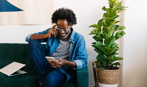 Mature man smiling and reading a message from his mobile phone at home