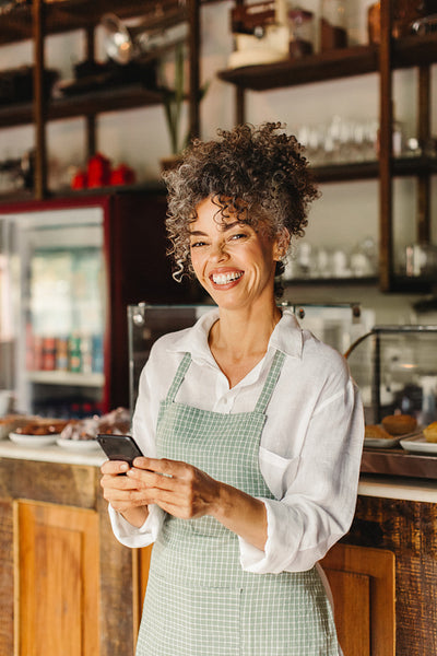 Business owner smiling while holding a smartphone