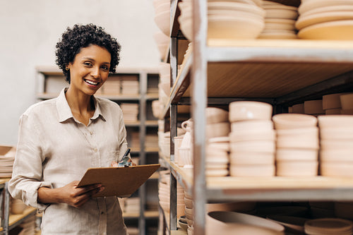 Young ceramist smiling at the camera in her shop