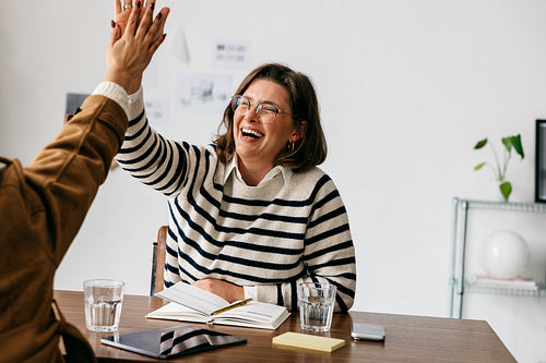 Collaboration drives business teamwork as a woman celebrates in a casual office meeting
