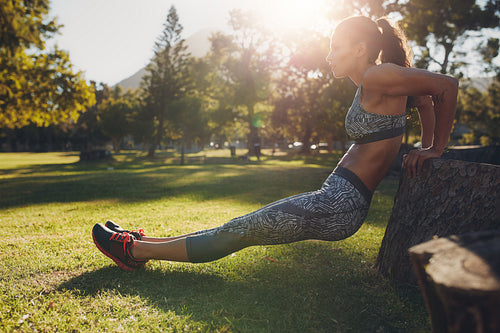 Strong young woman doing dips at the park