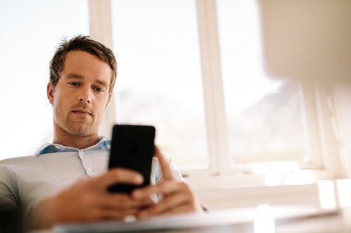 Freelancer looking at mobile phone sitting at home