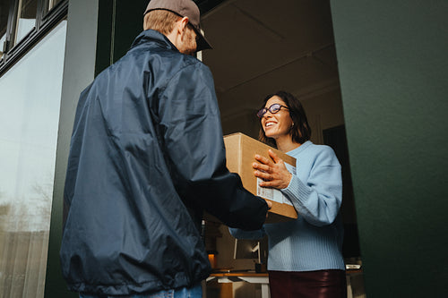 Office delivery reaches a woman as she accepts a package at the entrance