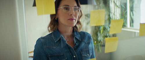 Businesswoman writes on sticky notes on glass wall in the office