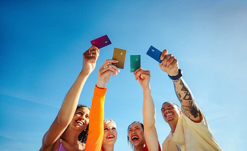 Young adults raise credit cards outdoors celebrating student financing