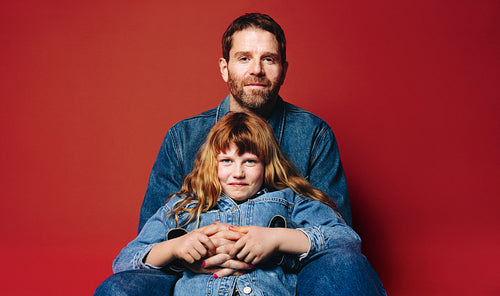 Sitting together, father and daughter show a close family bond in the studio