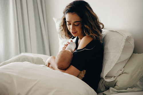 Mother feeding infant on a bed