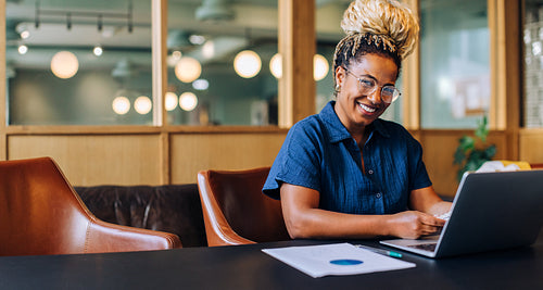 Smiling young professional woman in a casual office setting with laptop