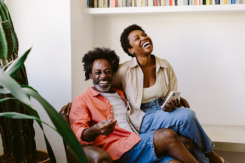 Mature black couple laughing and having a good time on a couch at home