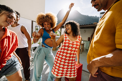 Group of friends dancing and smiling outdoors during a sunny day