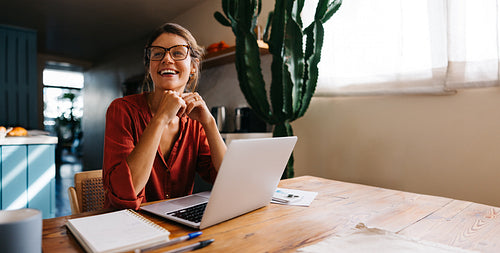 Woman smiling at laptop in bright kitchen