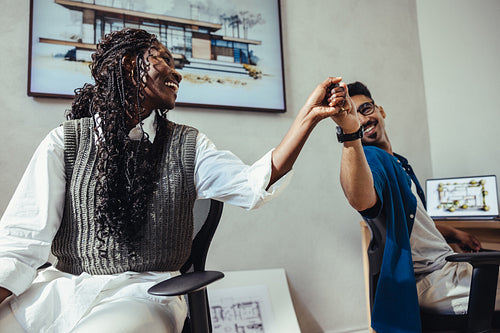 Colleagues celebrating teamwork success with a high five in creative office setting