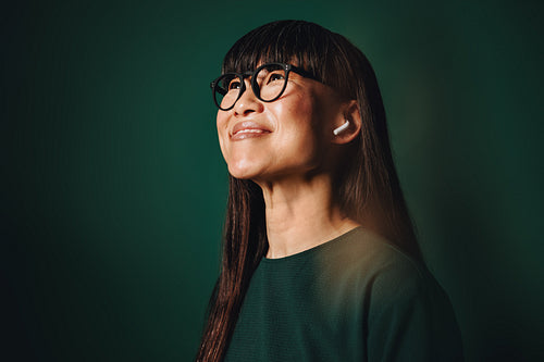 Glasses give the woman a thoughtful look as she listens in studio