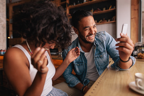 Couple at cafe taking selfie and laughing