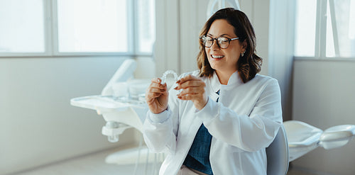 Female dentist demonstrates clear aligner in modern clinic setting
