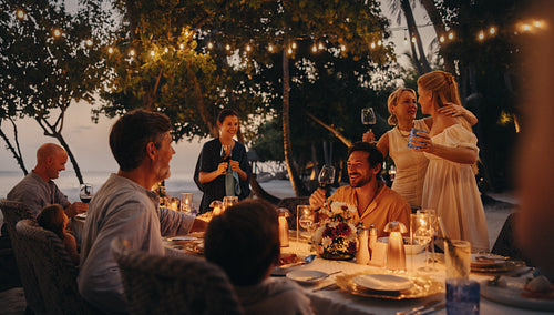 Luxurious family dining on a tropical island under twinkling lights