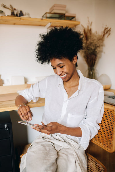 Woman jeweler checking phone in studio