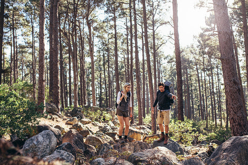 Hiking couple walking on rocks in forest wearing backpacks