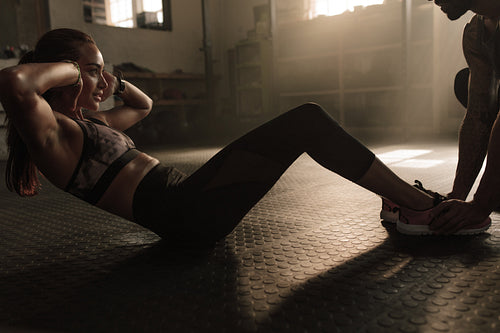 Woman doing sit-ups exercises with male instructor