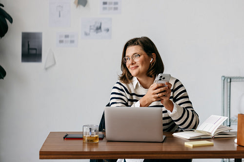 Her phone and laptop keep the woman connected at a relaxed desk
