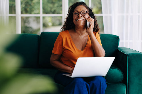 Happy mature woman calling her clients while working remotely