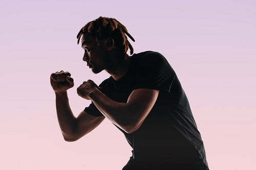 Confident athletic boxer in sportswear practices bare knuckle punches in studio silhouette