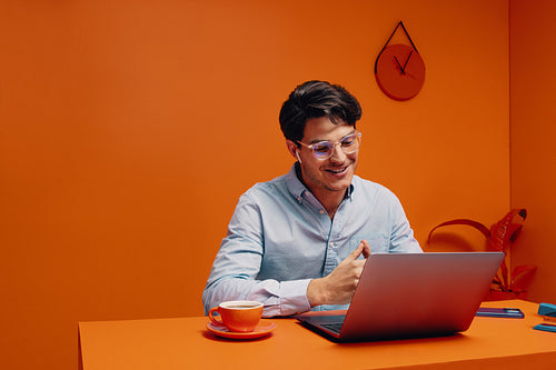 Male recruiter with eyeglasses and earpods working online and drinking coffee