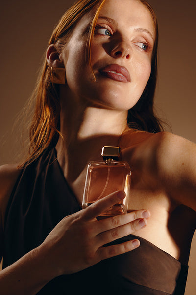 Woman holding perfume bottle in elegant portrait