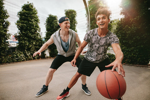 Happy teenagers playing basketball
