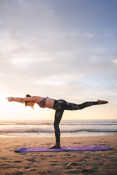 Fit young woman practicing yoga at beach