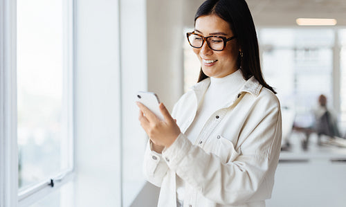 Female entrepreneur reading a text message on her mobile phone