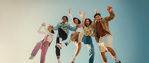 Group of friends laughing and jumping outdoors