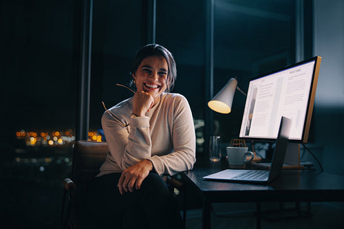 Late night productivity: Creative business woman smiling at the camera in her office