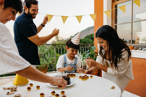Family celebrating a boy's birthday with a small party outdoors