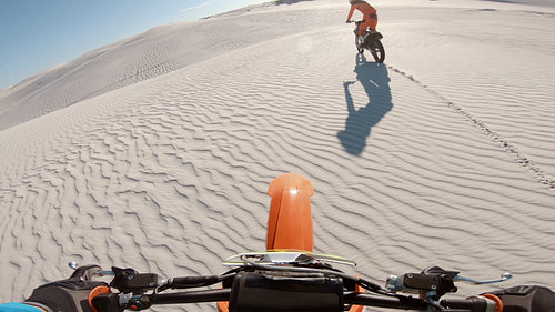 Motocross athlete racing behind his competitor in a desert
