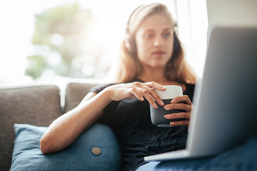 Female relaxing at home with cup of coffee and laptop