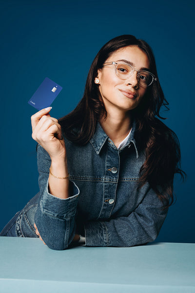 Credit card in hand, the woman poses in a blue banking studio portrait