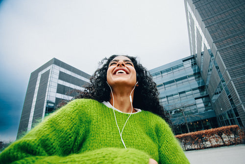 Outdoor city energy follows the woman as she walks with headphones and music