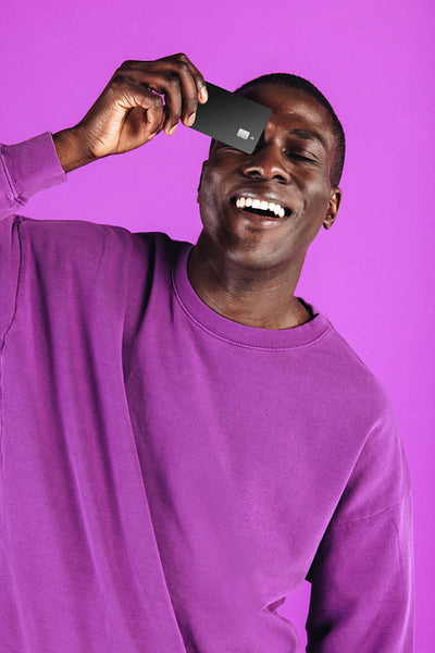 Embracing a card currency: Happy young man holding a black credit card in a studio