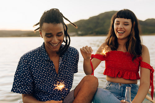Happy young couple having fun with Bengal lights during a vacati